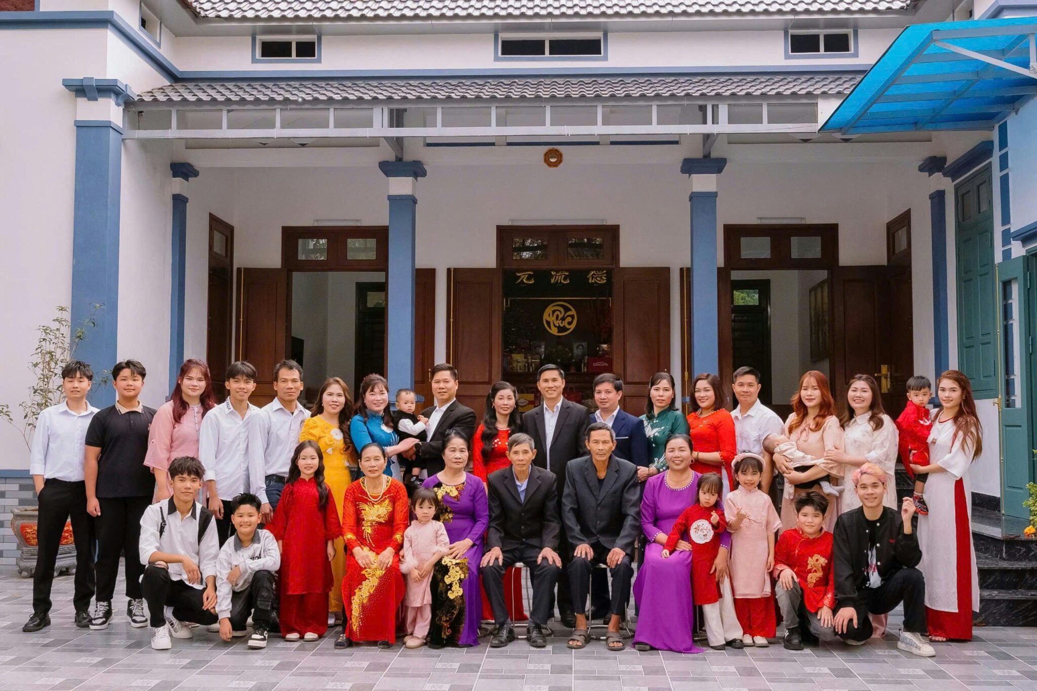 A large multi-generational family poses together outside their modern home.