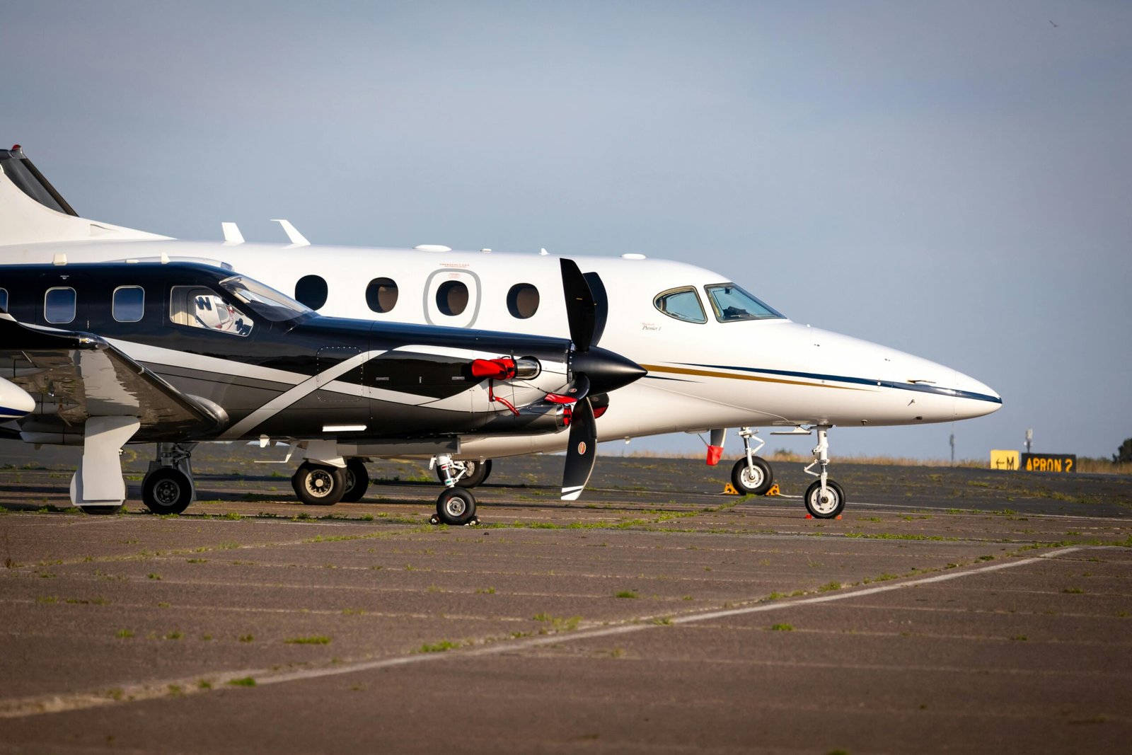 Luxury private aircraft parked on an airport tarmac, ready for departure under clear blue skies.